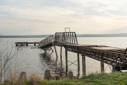 Abandoned iron pier or jetty on the river bank. The pier is already badly destroyed and is sinking in water. © Илья Мышенков