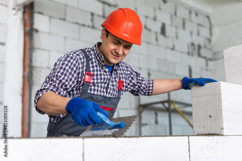 Bilde på lerret Bricklayer builder working with autoclaved aerated concrete blocks