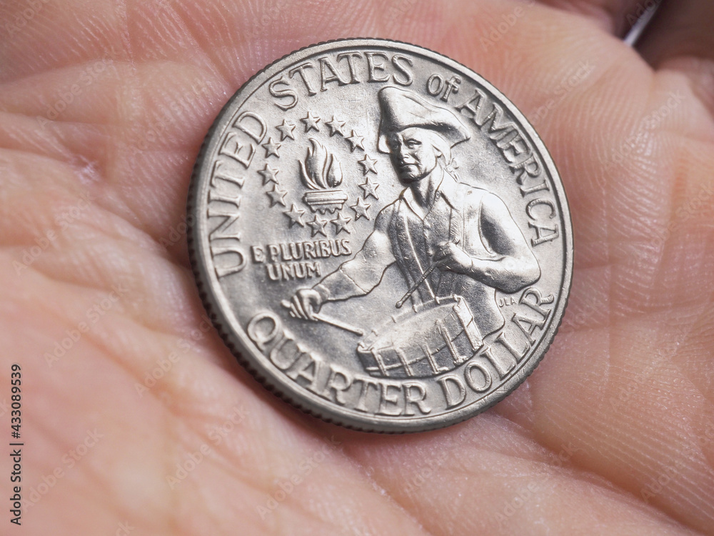 The US quarter dollar coin with drummer lies in a man's palm close-up. Illustration on the theme of American patriotism and Independence Day The US quarter dollar coin with drummer lies in a man's palm close-up. Illustration on the theme of American patriotism and Independence Day