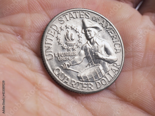 The US quarter dollar coin with drummer lies in a man's palm close-up. Illustration on the theme of American patriotism and Independence Day