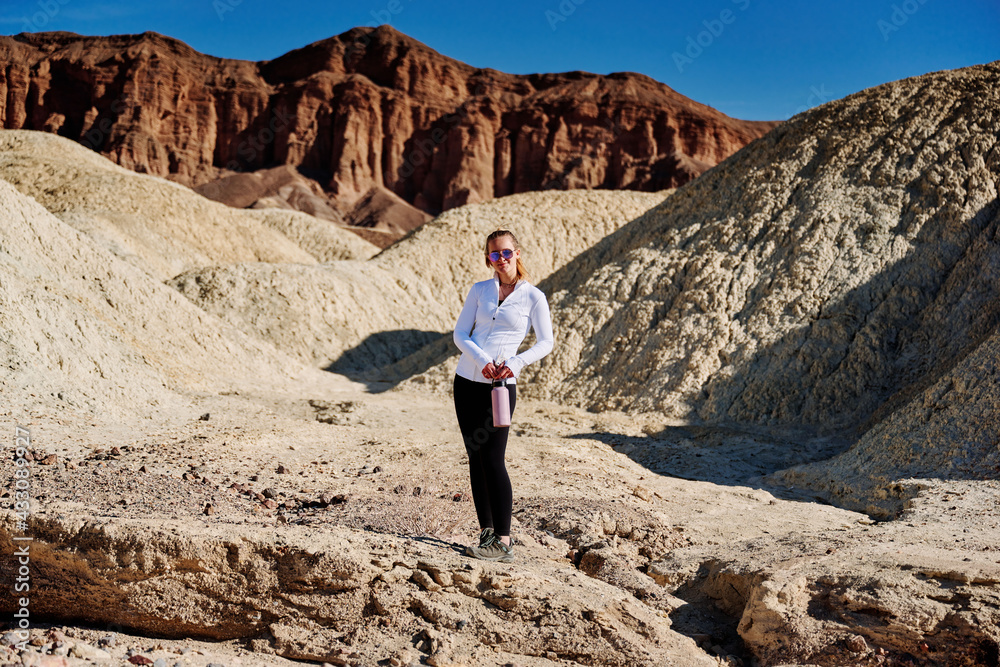 A family hike from Zabriskie Point in Death Valley national park in california. Huge sand dunes, terracotta mountains and hazy horizons are shining against clear blue sky in the midday sun.