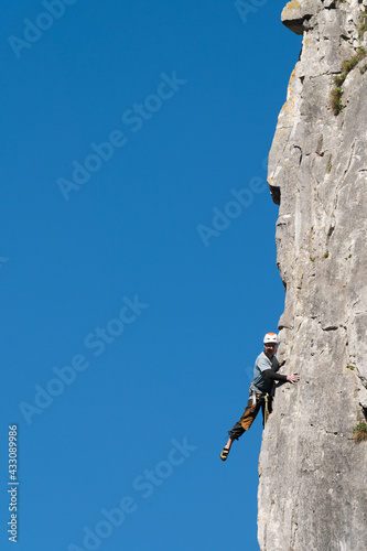 Climber poses throwing his leg into the void during rock climbing.