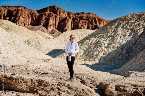 A family hike from Zabriskie Point in Death Valley national park in california. Huge sand dunes  terracotta mountains and hazy horizons are shining against clear blue sky in the midday sun.