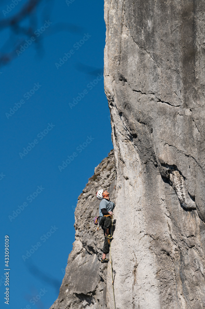 Latin male climber pulls the rope while ascending a route. Latin male climber pulls the rope while ascending a route.