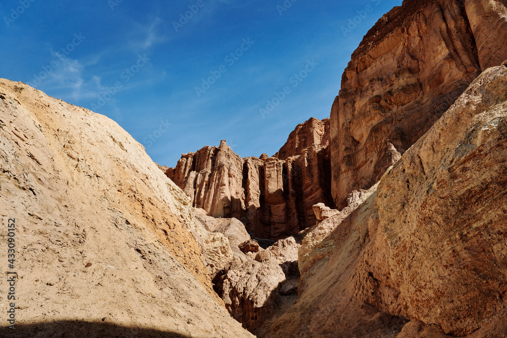 A family hike from Zabriskie Point in Death Valley national park in california. Huge sand dunes, terracotta mountains and hazy horizons are shining against clear blue sky in the midday sun.