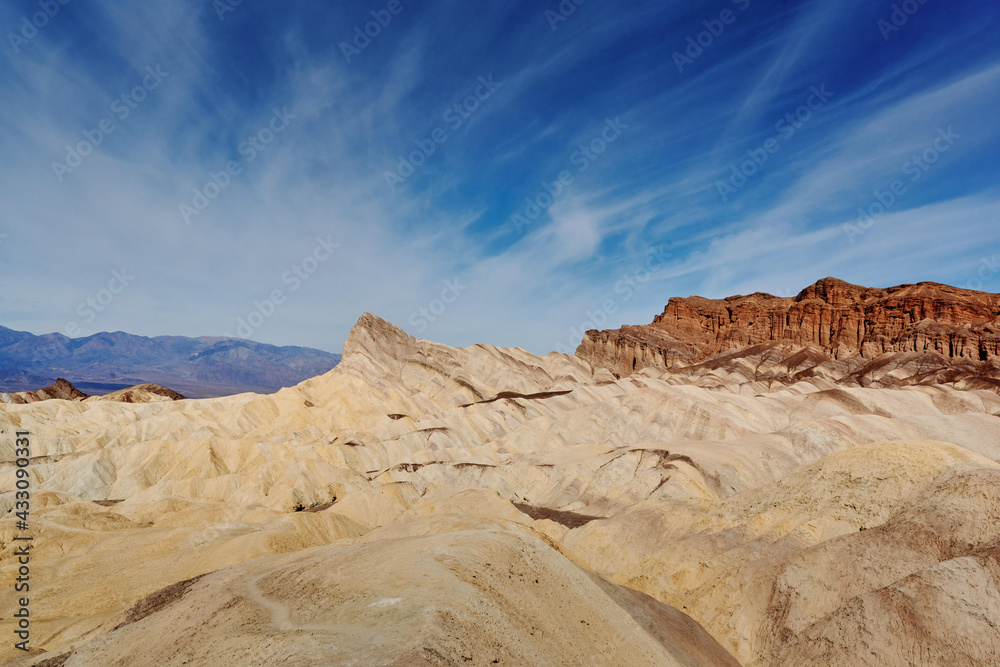Fototapeta premium A family hike from Zabriskie Point in Death Valley national park in california. Huge sand dunes, terracotta mountains and hazy horizons are shining against clear blue sky in the midday sun.