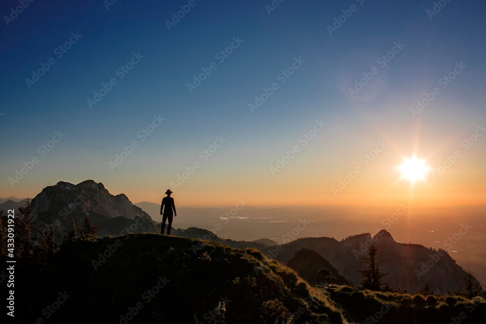 Ausblick eines Wanderers bei seiner Wandertour in die Ferne in den Bergen weit oben beim Sonnenaufgang 