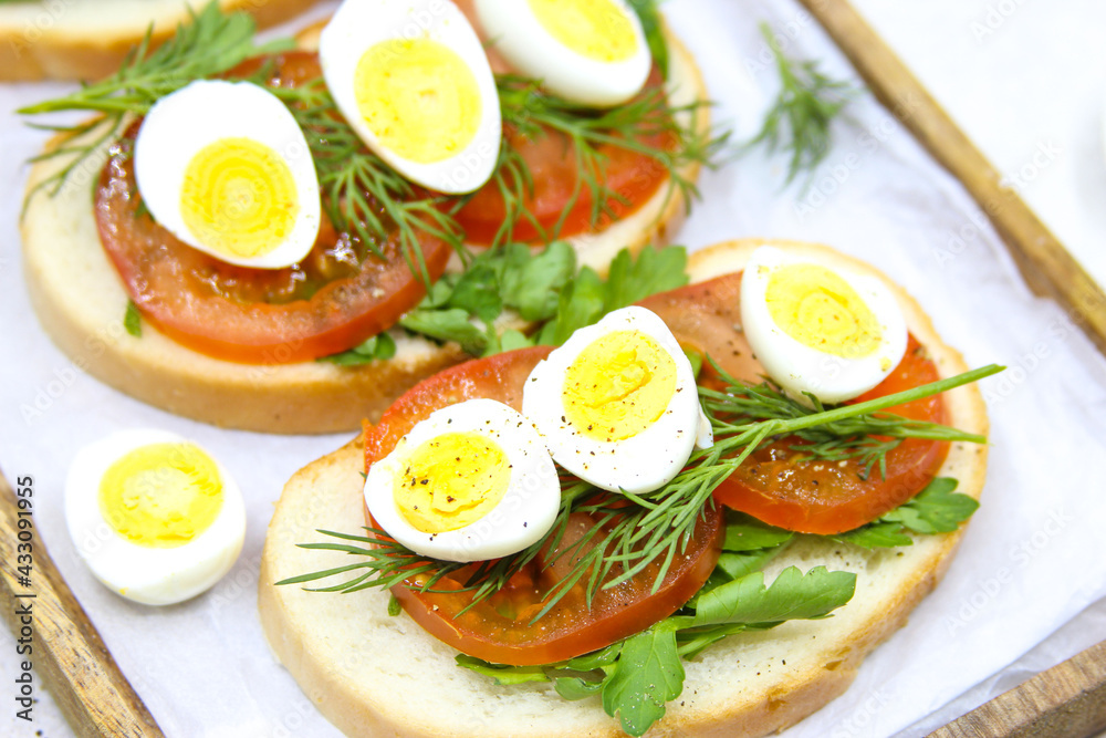 Fresh toast sandwiches with quail eggs, tomatoes and green herbs. Closeup. Top view. 