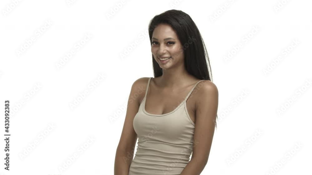Video of attractive african-american girl in beige tank top, looking silly and happy, flirting with you, smiling cute, standing over white background Video of attractive african-american girl in beige tank top, looking silly and happy, flirting with you, smiling cute, standing over white background