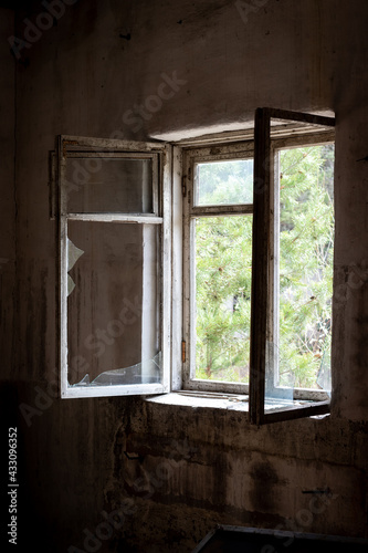 Dirty old open window with broken glass in abandoned house in ghost town Pripyat, Chernobyl Exclusion Zone, Ukraine. Vertical photo