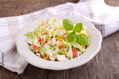 Salad of cabbage with grains corn and crab sticks in a plate on an old background.
