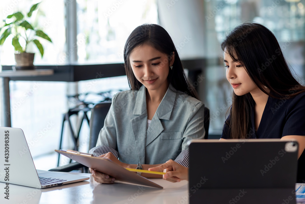 Group of young Asian beautiful businesswoman analyzed collaboration pointed document at the tablet placed at the office table. Group of young Asian beautiful businesswoman analyzed collaboration pointed document at the tablet placed at the office table.