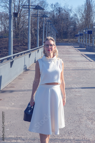 blonde woman in white dress standing outside at sunny day on street