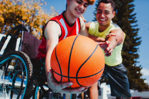 mexican man using wheelchair and playing basketball with a friend disability concept