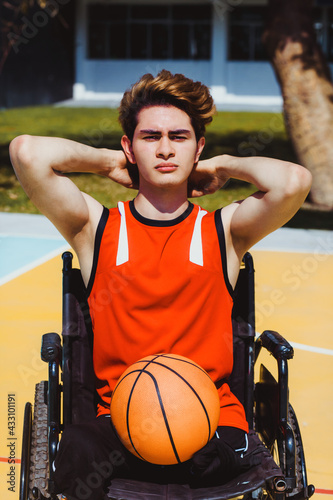 portrait of mexican young man using wheelchair and playing basketball disability concept