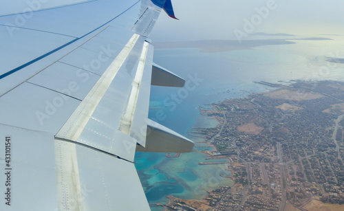 Airplane wing on the background of the blue sea with corals