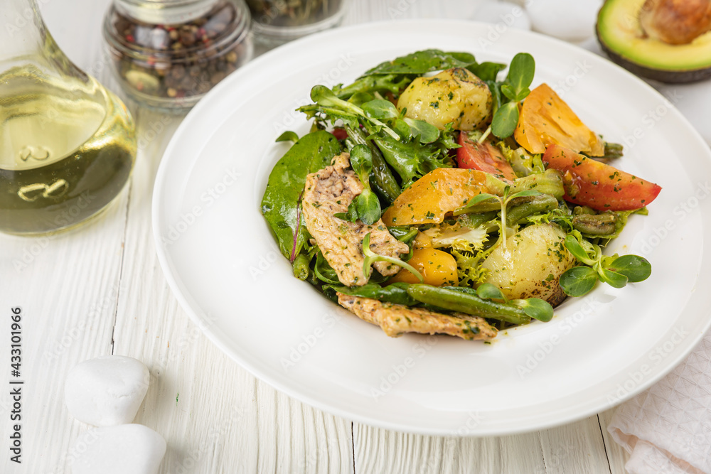 Grilled chicken salad, tomatoes, potatoes and greens. On a white plate and white table.
Grilled chicken salad, tomatoes, potatoes and greens. On a white plate and white table.