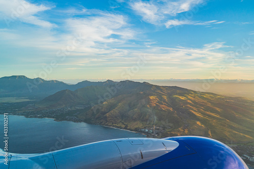View of the tropical island of O ahu from above over wing during golden hour