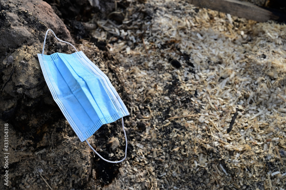 On the ground is a used disposable medical mask. Problems of environmental pollution and medical waste disposal On the ground is a used disposable medical mask. Problems of environmental pollution and medical waste disposal