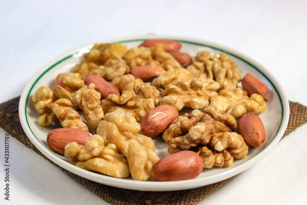 Peeled walnuts and peanuts on a saucer close-up.