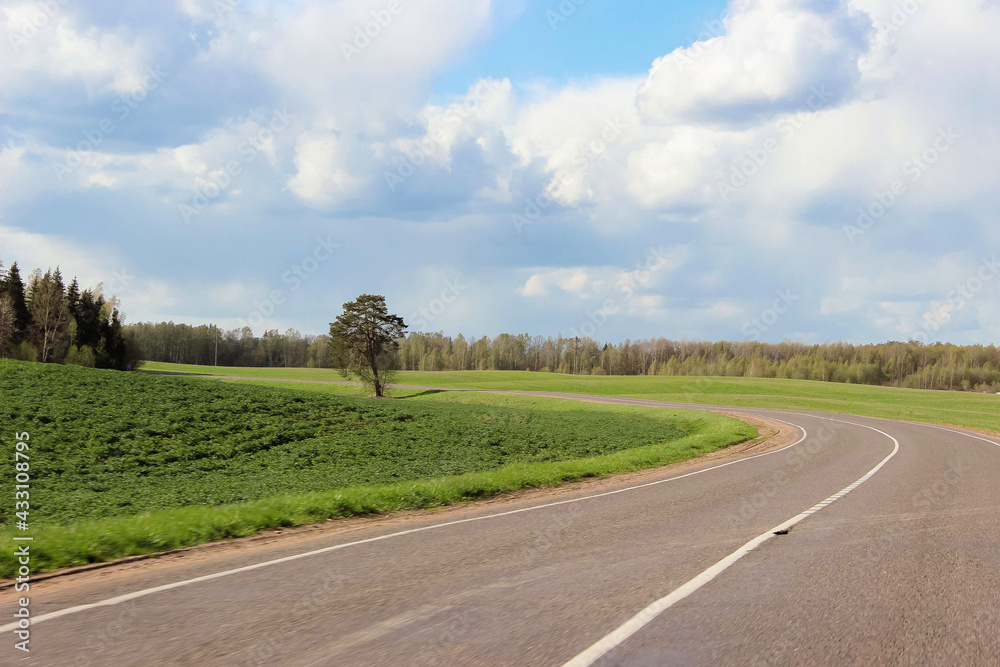 Naklejka premium Road in the fields and blue sky