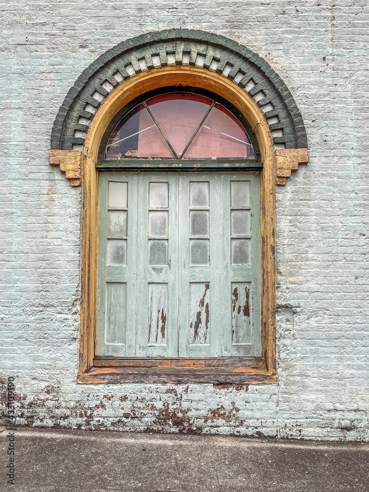 Fototapeta premium Worn doors on brick building with decorative brick arch
