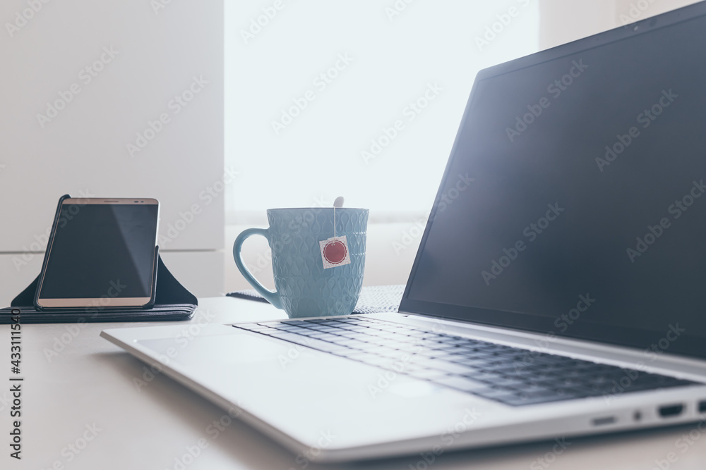 laptop on white table with cup of tea. Work at home laptop on white table with cup of tea. Work at home