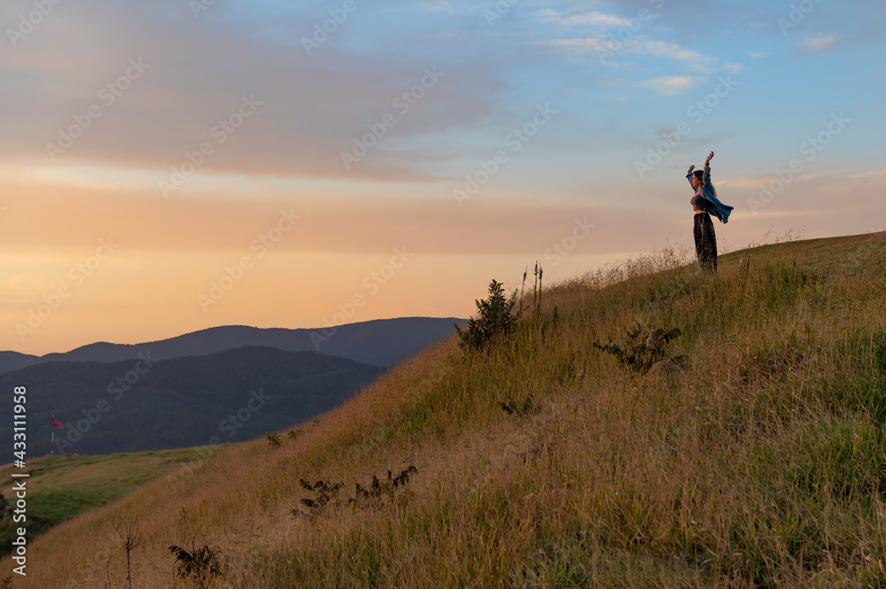 happy .young tourist woman with flying hair at panoramic view on high mountain at sunset. A borometer is behi