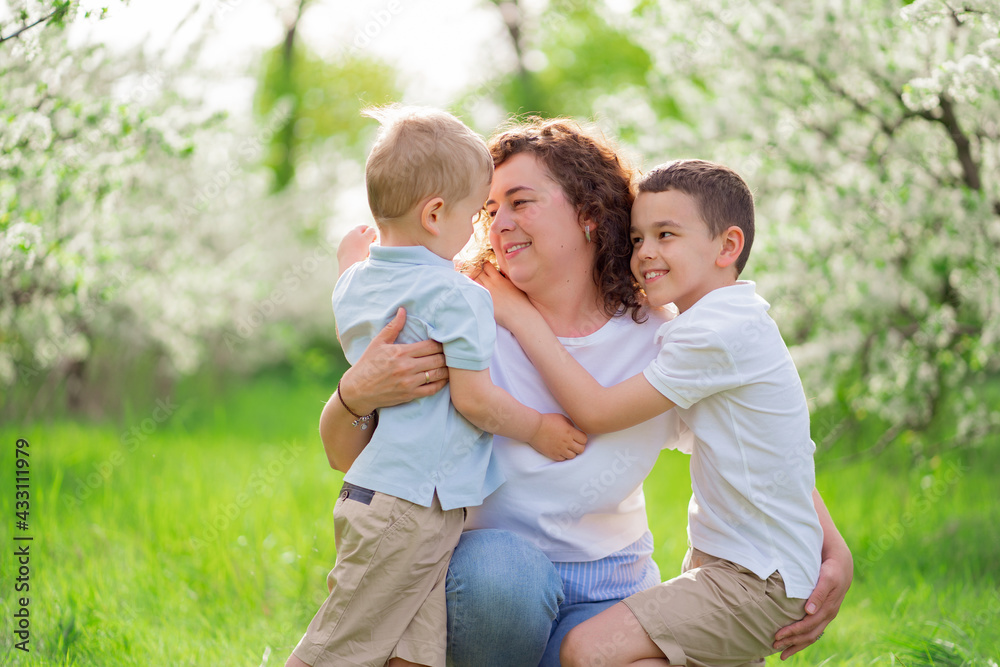 mother with sons cuddle in flowering garden. mother's day mother with sons cuddle in flowering garden. mother's day