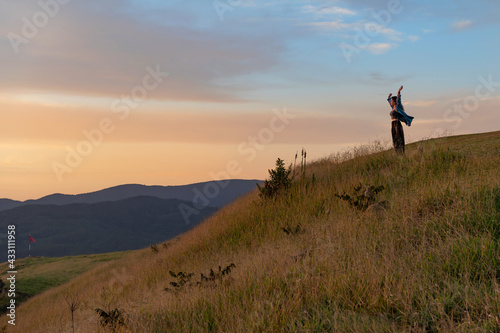 happy .young tourist woman with flying hair at panoramic view on high mountain at sunset. A borometer is behi