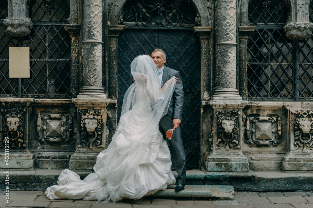 Bride and groom posing next an old church. Stylish wedding couple portrait of the newlyweds.