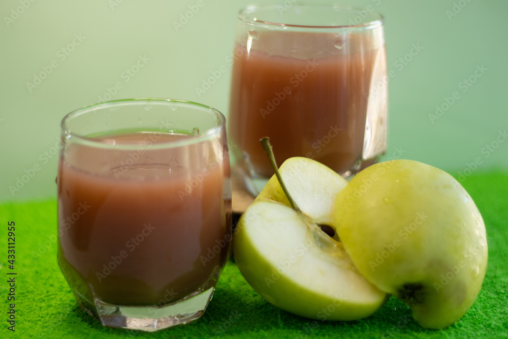 two glasses of fresh juice on a green background