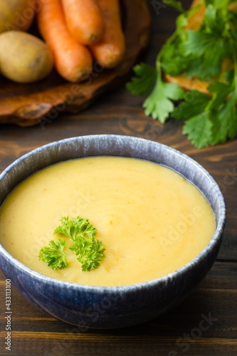 Freshly cooked potato soup in a bowl garnished with parsley and main ingredients in the back