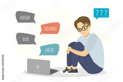 Cyber bullying. Sad boy sitting and uses laptop. Hate speeches on screen. Unhappy caucasian schoolboy under pressure. Male student has problems with discrimination