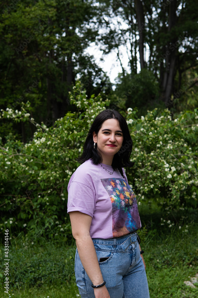 Photo of an attractive woman with black hair in the middle of nature during spring time, walking around and smiling during a sunny day Photo of an attractive woman with black hair in the middle of nature during spring time, walking around and smiling during a sunny day