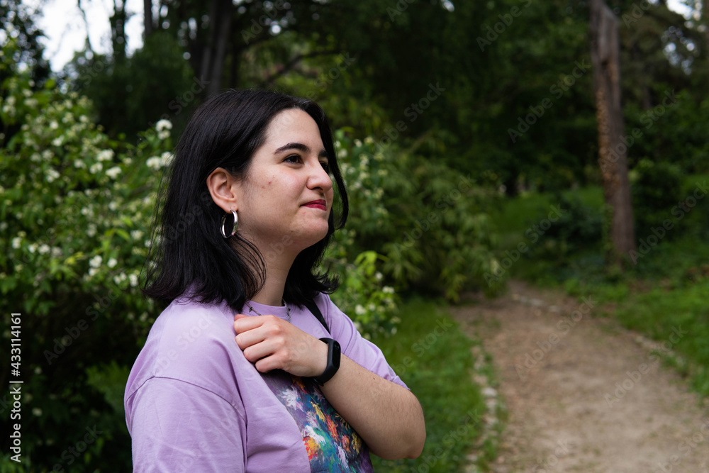 Photo of an attractive woman with black hair in the middle of nature during spring time, walking around and smiling during a sunny day Photo of an attractive woman with black hair in the middle of nature during spring time, walking around and smiling during a sunny day