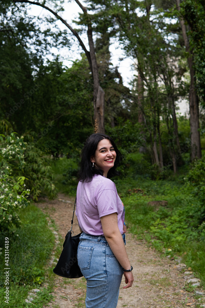 Photo of an attractive woman with black hair in the middle of nature during spring time, walking around and smiling during a sunny day Photo of an attractive woman with black hair in the middle of nature during spring time, walking around and smiling during a sunny day
