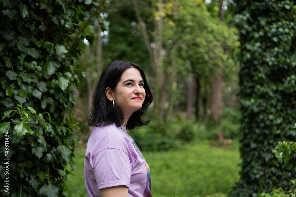 Photo of an attractive woman with black hair in the middle of nature during spring time, walking around and smiling during a sunny day Photo of an attractive woman with black hair in the middle of nature during spring time, walking around and smiling during a sunny day