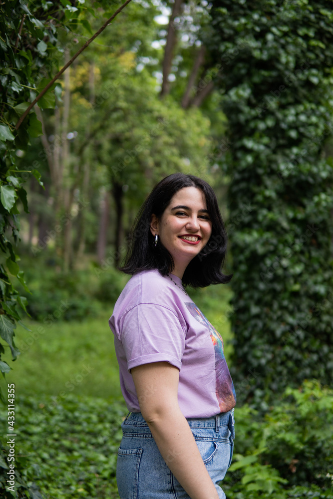 Photo of an attractive woman with black hair in the middle of nature during spring time, walking around and smiling during a sunny day Photo of an attractive woman with black hair in the middle of nature during spring time, walking around and smiling during a sunny day