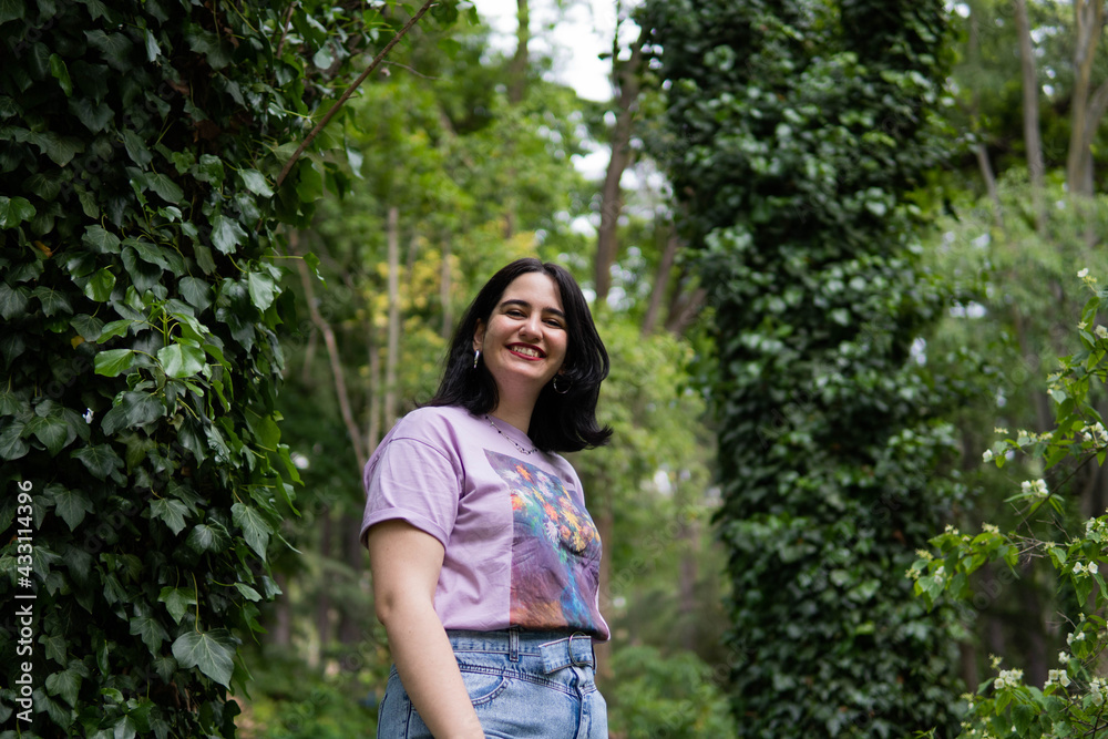 Photo of an attractive woman with black hair in the middle of nature during spring time, walking around and smiling during a sunny day Photo of an attractive woman with black hair in the middle of nature during spring time, walking around and smiling during a sunny day