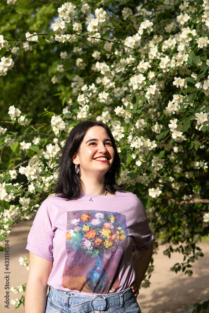 Photo of an attractive woman with black hair in the middle of nature during spring time, walking around and smiling during a sunny day Photo of an attractive woman with black hair in the middle of nature during spring time, walking around and smiling during a sunny day