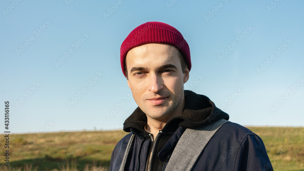 Nice man on the background of a beautiful landscape looks at the camera, close-up, 16:9