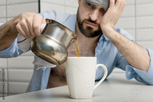 Sleepy man pours invigorating morning coffee, close-up, cropped image, close-up