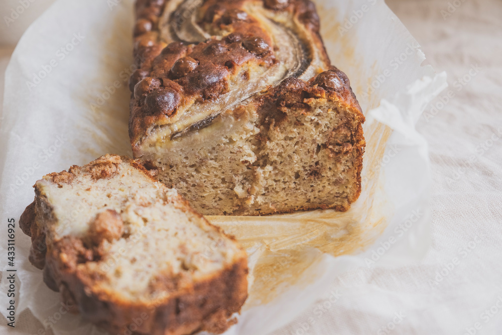 Delicious freshly baked banana bread with chocolate chips on white tablecloth background. Sweet vegan gluten free food, from above. Homemade baked goods.