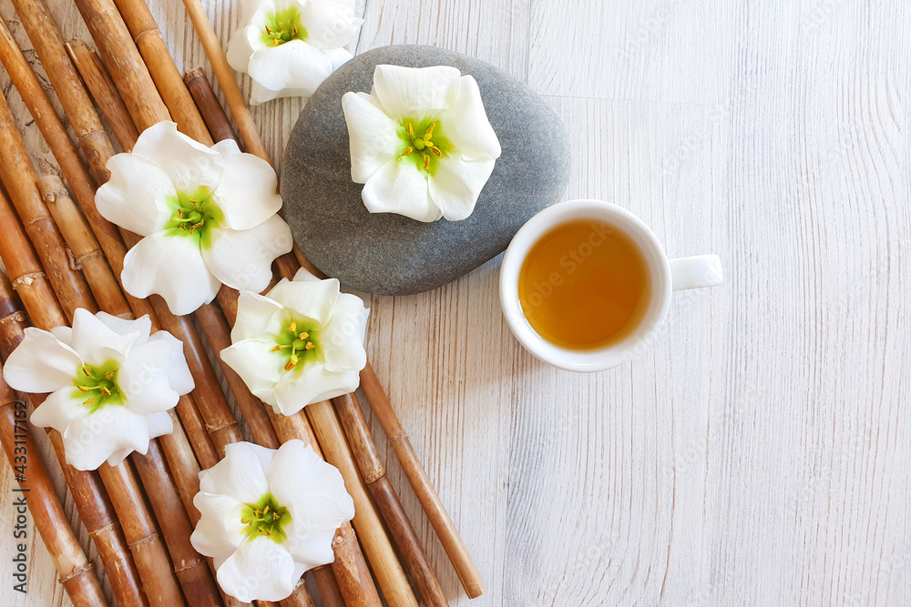 herbal tea in white cup, bamboo and flowers. Top view