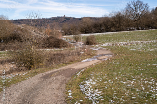 Country road in the landscape with a little snow in the fields 