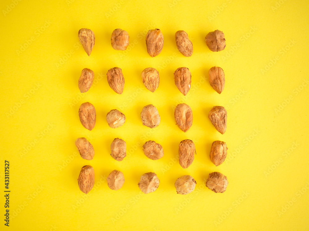 Hazelnuts on a neon yellow background. Hazelnut cube as a pattern. Pattern of peeled hazelnuts. Illuminating yellow background in hazel properly arranged. Hazelnut cube shape. Hazelnuts on a neon yellow background. Hazelnut cube as a pattern. Pattern of peeled hazelnuts. Illuminating yellow background in hazel properly arranged. Hazelnut cube shape.