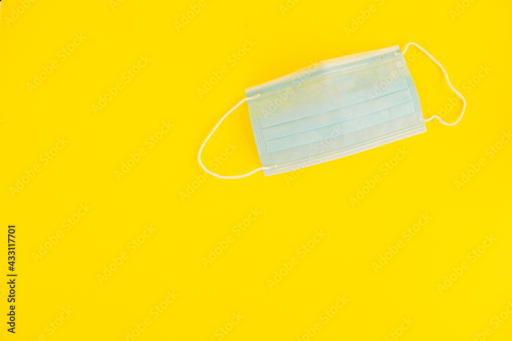 Face mask on a neon yellow background. Blue face mask. Neon yellow color as the trend of the year. Self-care. Inner life. Wear a face mask as protection against infectious diseases. Face mask on a neon yellow background. Blue face mask. Neon yellow color as the trend of the year. Self-care. Inner life. Wear a face mask as protection against infectious diseases.