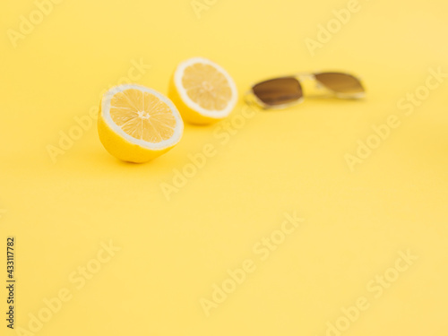 Two halves of lemon on illuminating yellow color and sunglasses. It's summer, enjoy. Minimalist photo showing the serenity of flight. Self-care and eat summer fruit. Lemon as a source of vitamins.