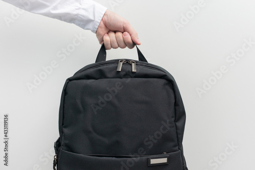 Man's hand with backpack, man takes a black backpack on a travel, white background, cropped image, copy space